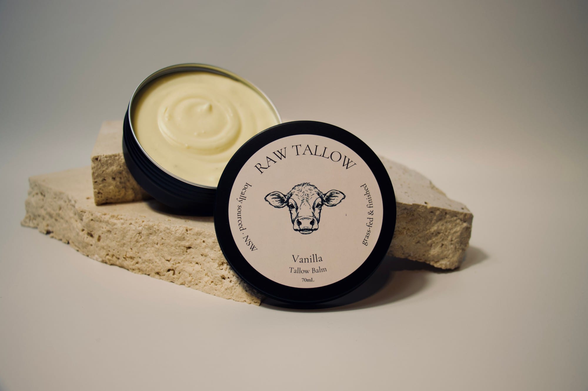Black amber jar of Raw Tallow Vanilla Tallow Balm with cream label and vanilla pod set styling